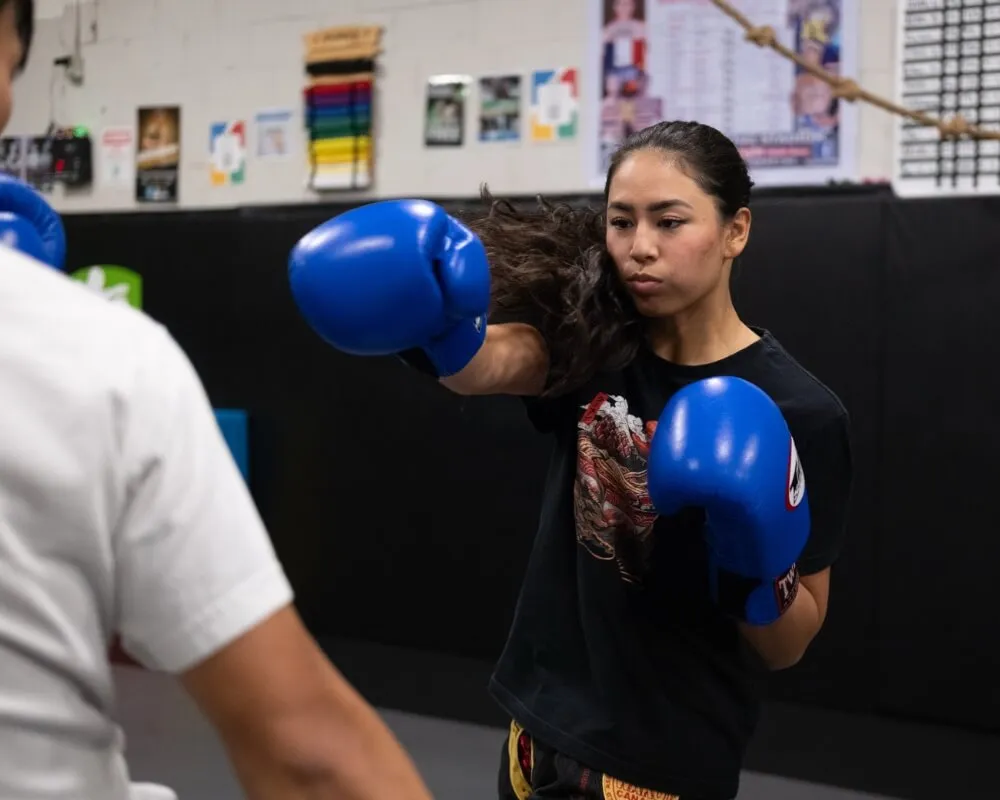 Woman practising a punch with blue boxing gloves