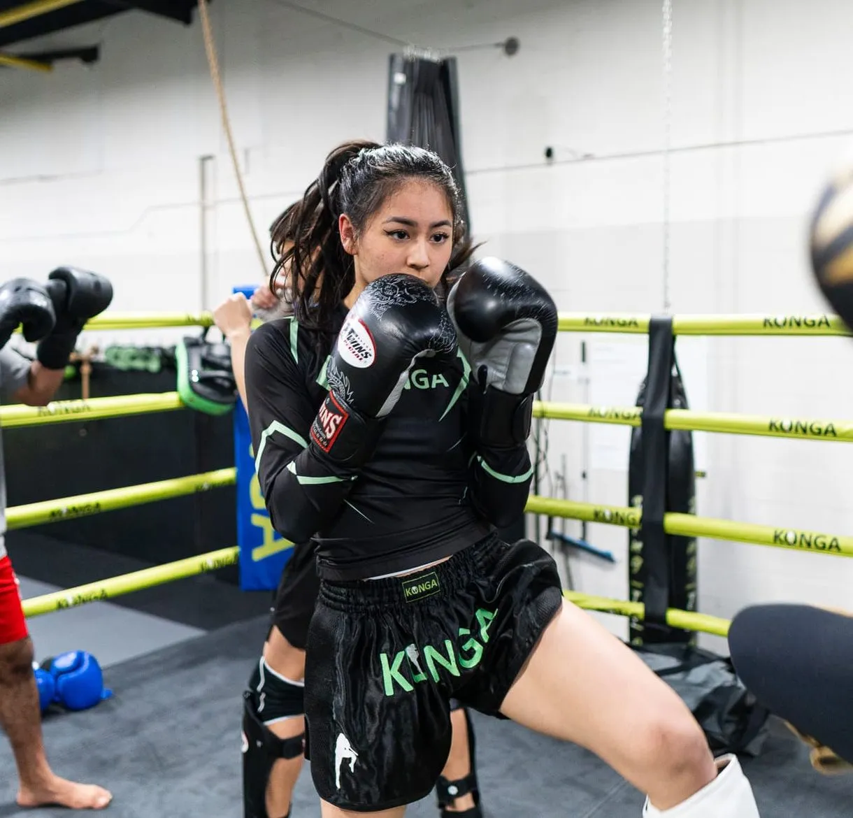 Woman holding a boxing stance with gloves inside the ring