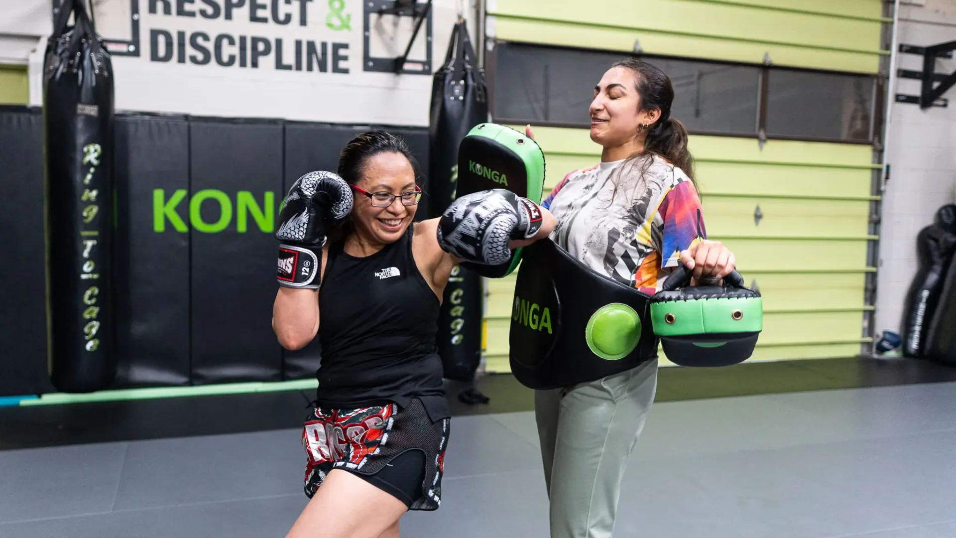 Two women practising punches with focus mitts